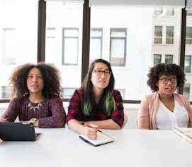 three women sitting at a table with a laptop