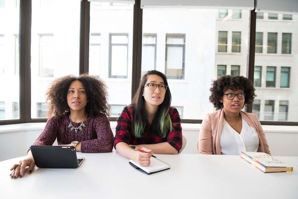 three women sitting at a table with a laptop