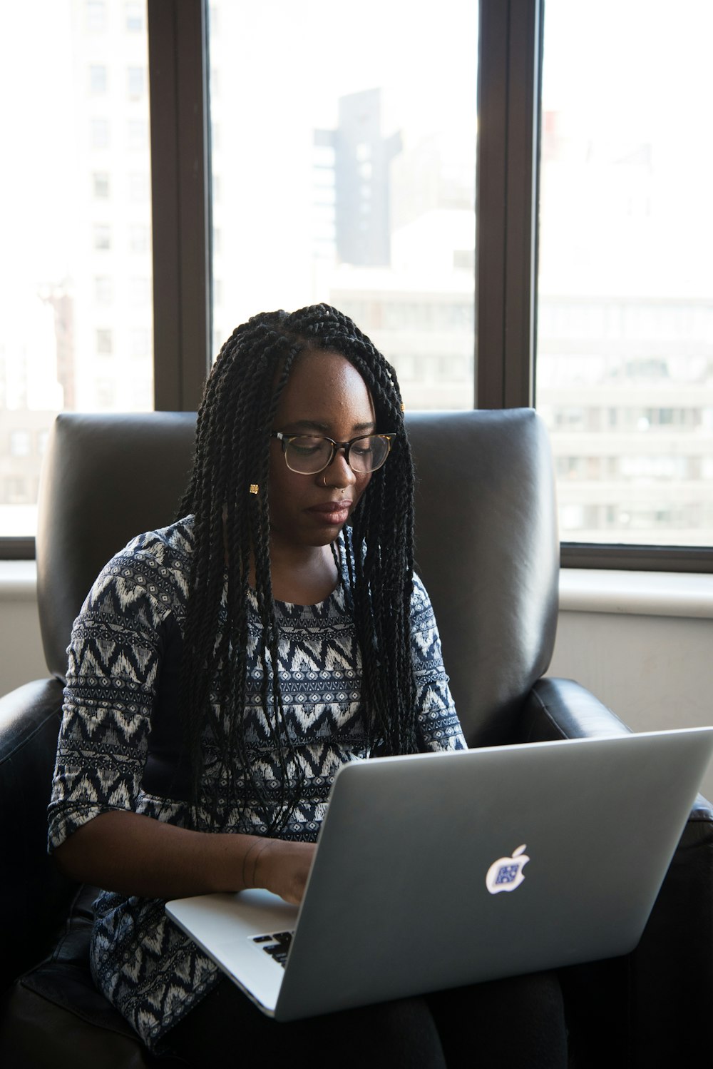 woman using MacBook while sitting on a sofa chair