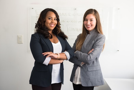 two women in suits standing beside wall