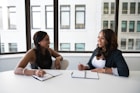 two women taking to each other while holding pens
