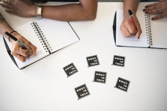two people writing on notebooks