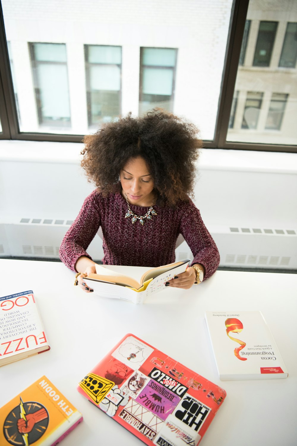 Frau sitzt am Tisch und liest Buch