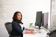 shallow focus photo of woman in black jacket using iMac
