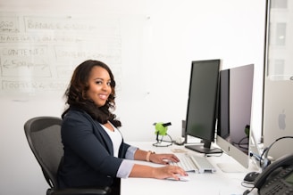 shallow focus photo of woman in black jacket using iMac
