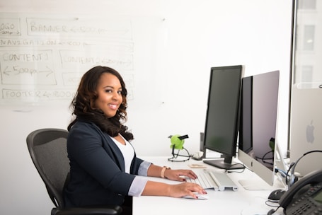shallow focus photo of woman in black jacket using iMac