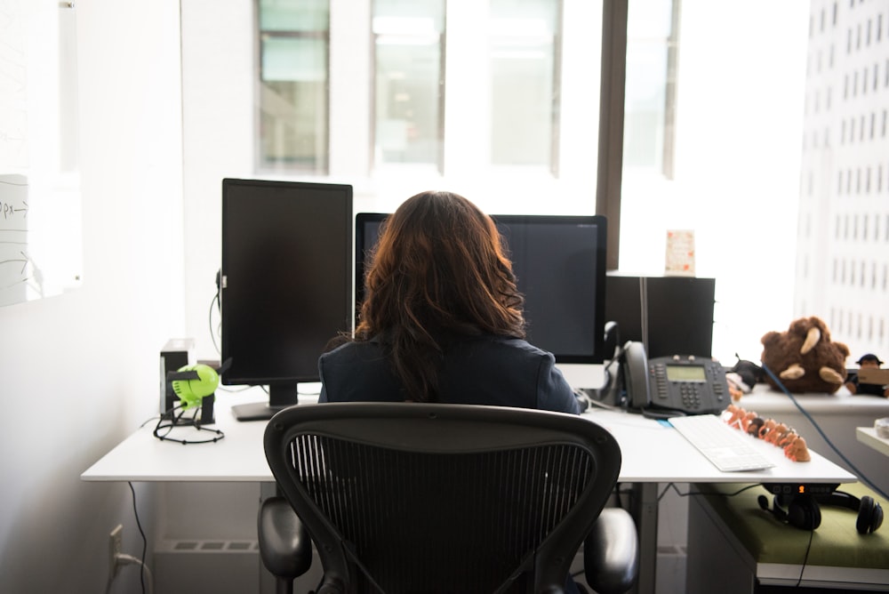 woman sitting on chair front of desk with desktop