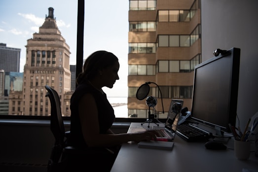 woman sitting in front of desk with computer monitor and keyboard on top