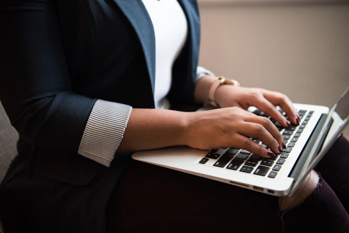 A focused professional typing a proposal on a laptop in a bright, modern office.