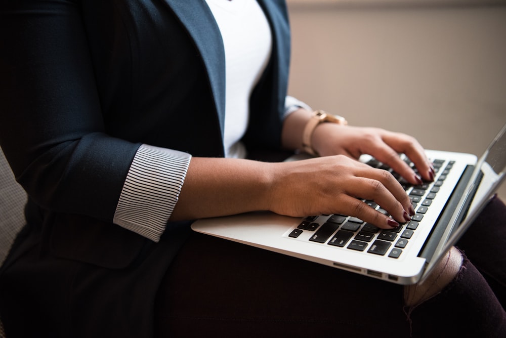 woman sitting and using laptop on her lap