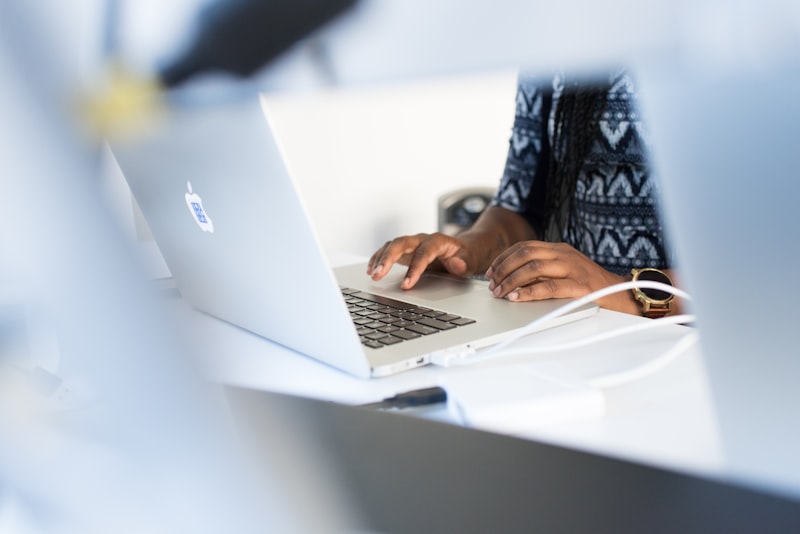 Person working at a clean desk with an open laptop, notebook nearby, in a quiet office setting