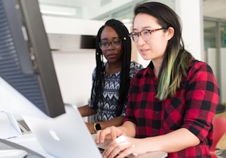 woman wearing red and black checkered blouse using flat screen computer