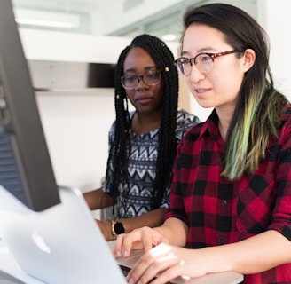 woman wearing red and black checkered blouse using flat screen computer