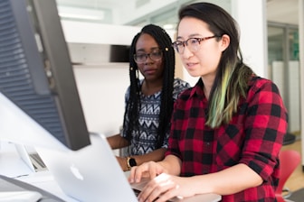 woman wearing red and black checkered blouse using flat screen computer