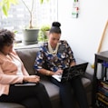 two woman siting on sofa inside room