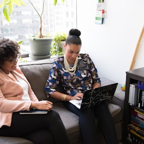 two woman siting on sofa inside room