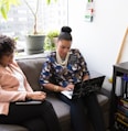 two woman siting on sofa inside room