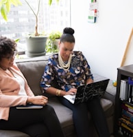 two woman siting on sofa inside room