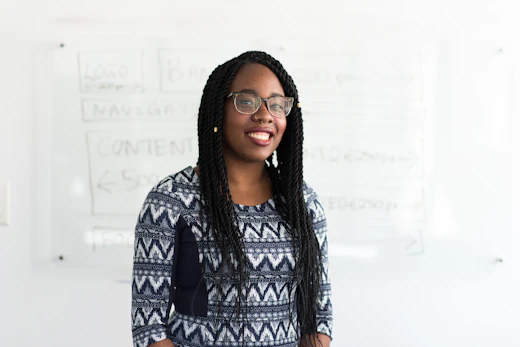 A smiling teacher standing in front of a whiteboard.