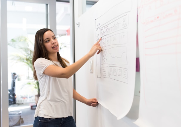 woman standing pointing paper on board