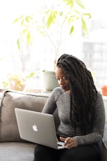 woman sitting on sofa with Macbook on her lap