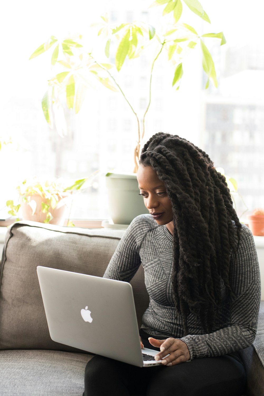 woman sitting on sofa with Macbook on her lap