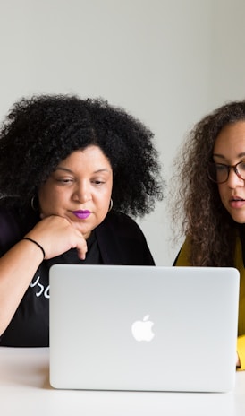 two women looking at the screen of a MacBook