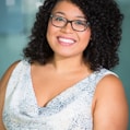 woman in brown-framed eyeglasses and white and gray cowl-neckline sleeveless top