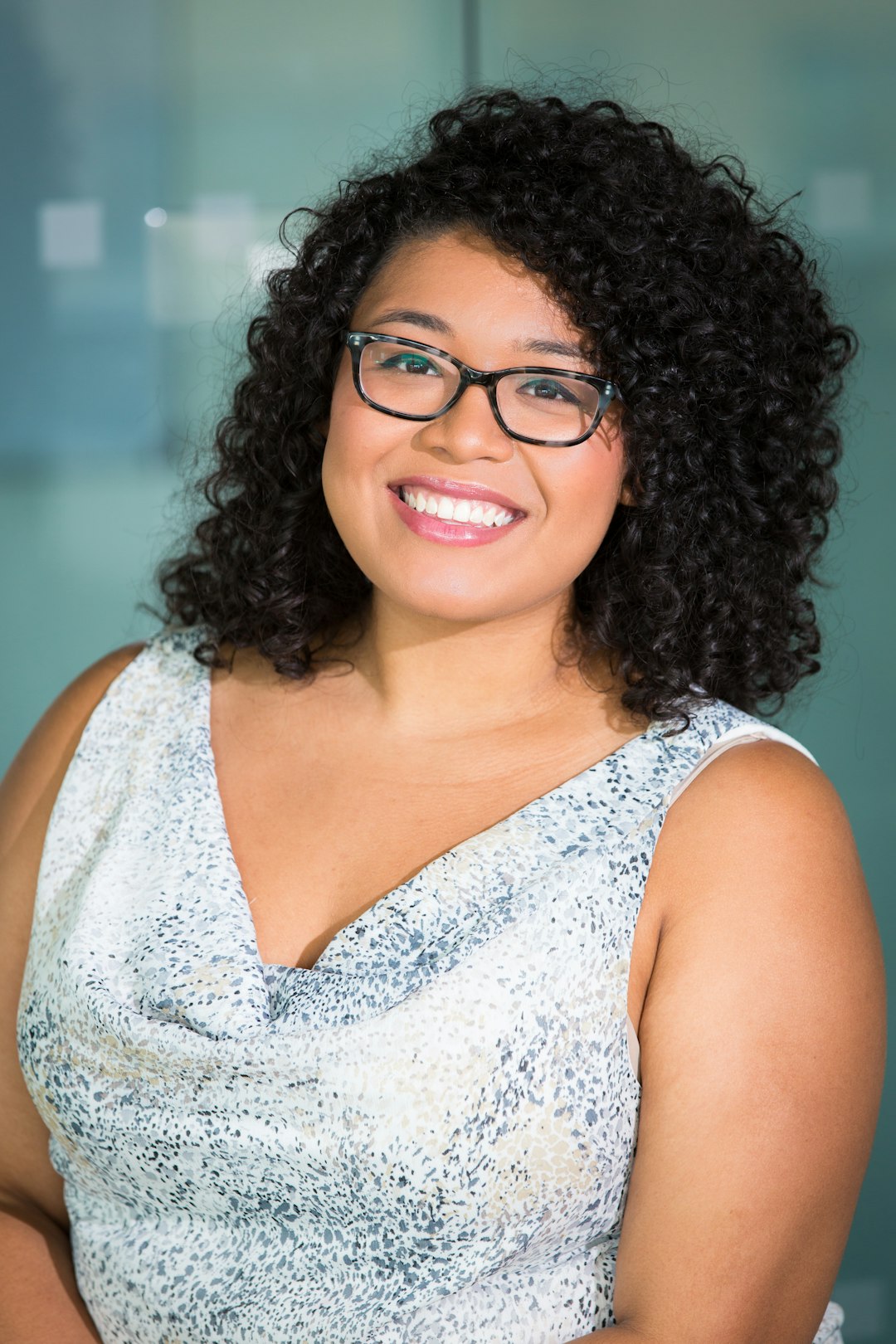 woman in brown-framed eyeglasses and white and gray cowl-neckline sleeveless top