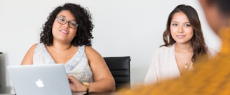 two women looking at person across the table