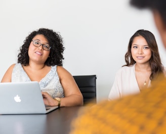 two women looking at person across the table