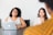 Two women are sitting at a table, engaged in a conversation. One woman is using a laptop placed in front of her. Both appear attentive and focused.