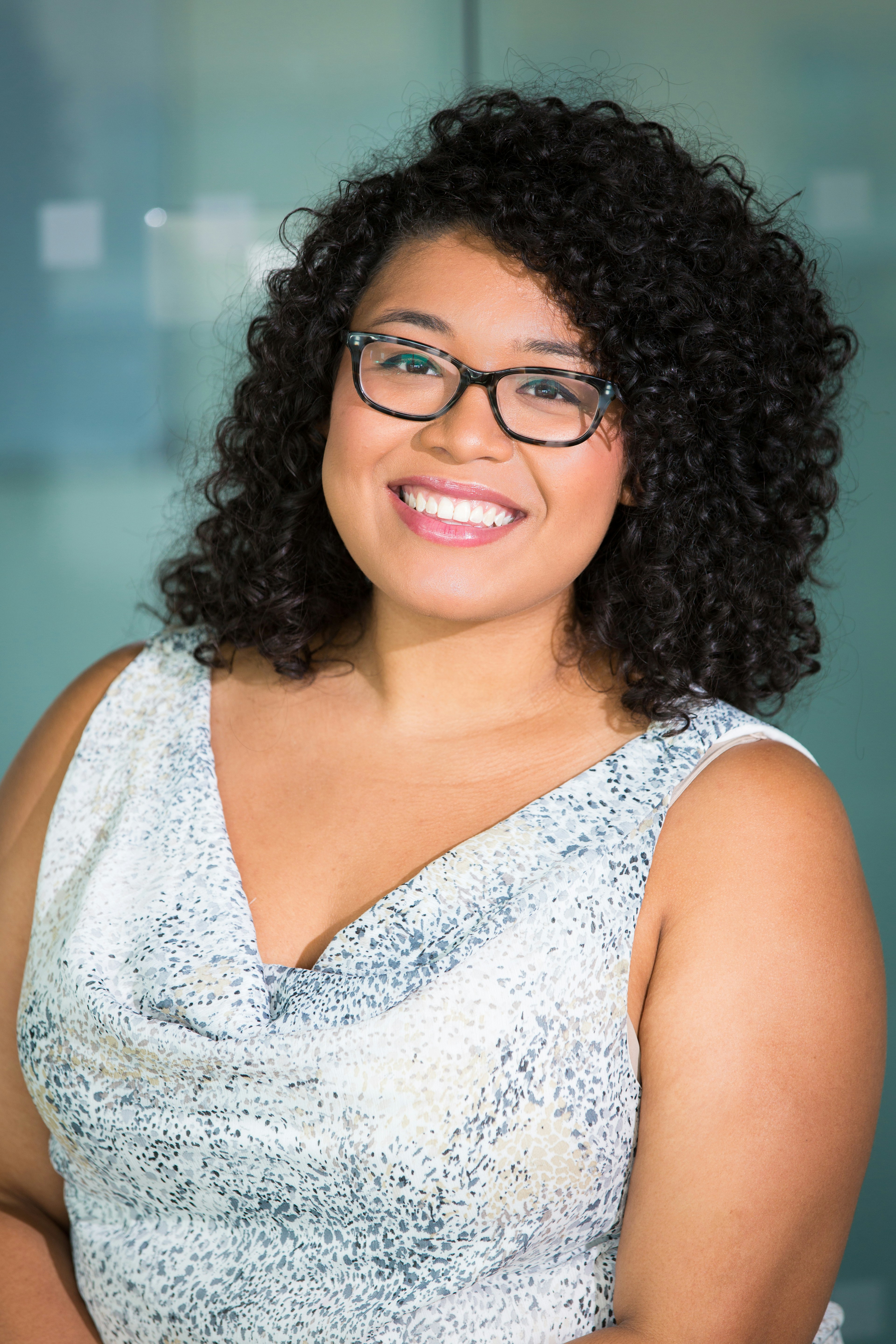 woman in brown-framed eyeglasses and white and gray cowl-neckline sleeveless top 