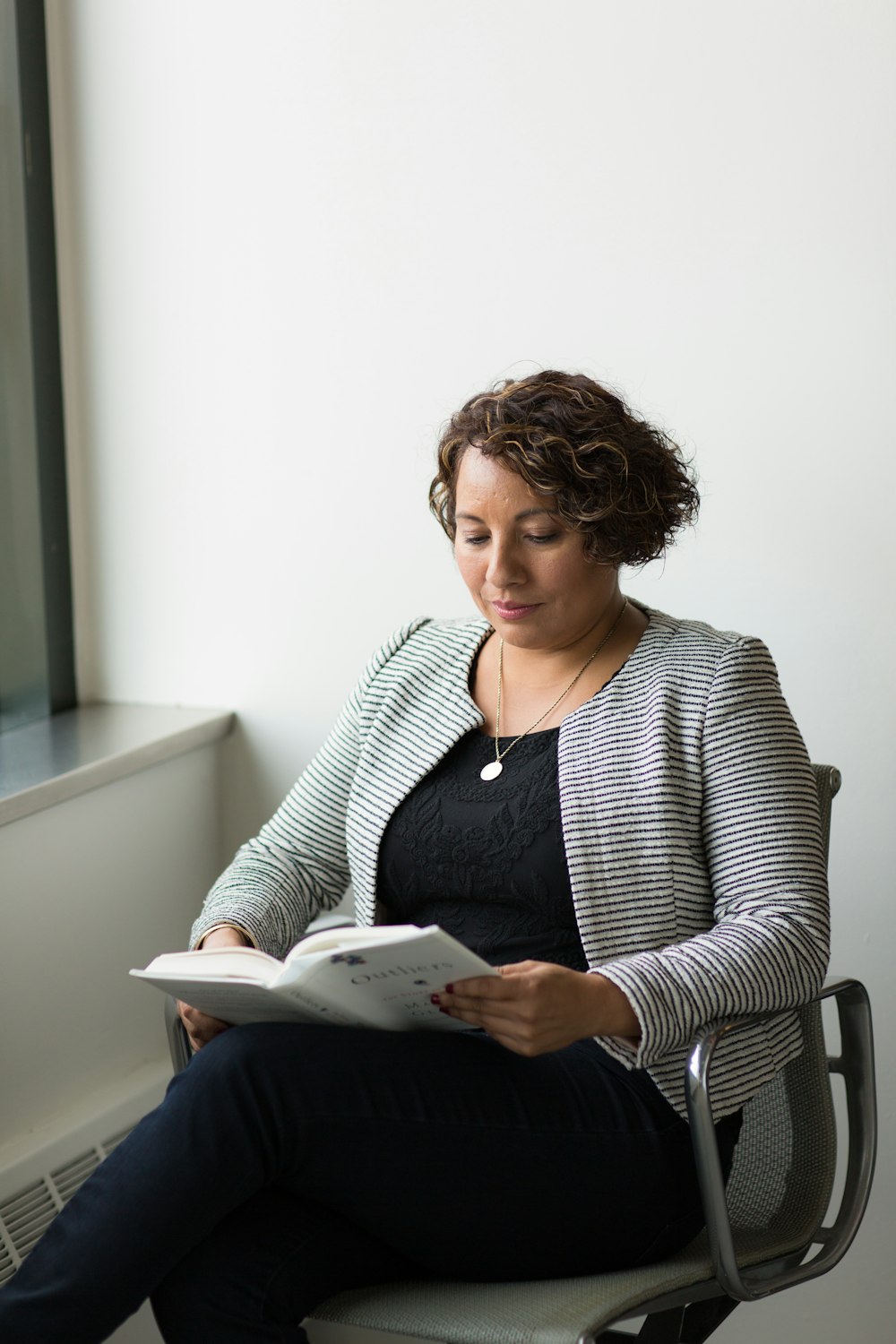 mulher de perna cruzada sentada e lendo o livro