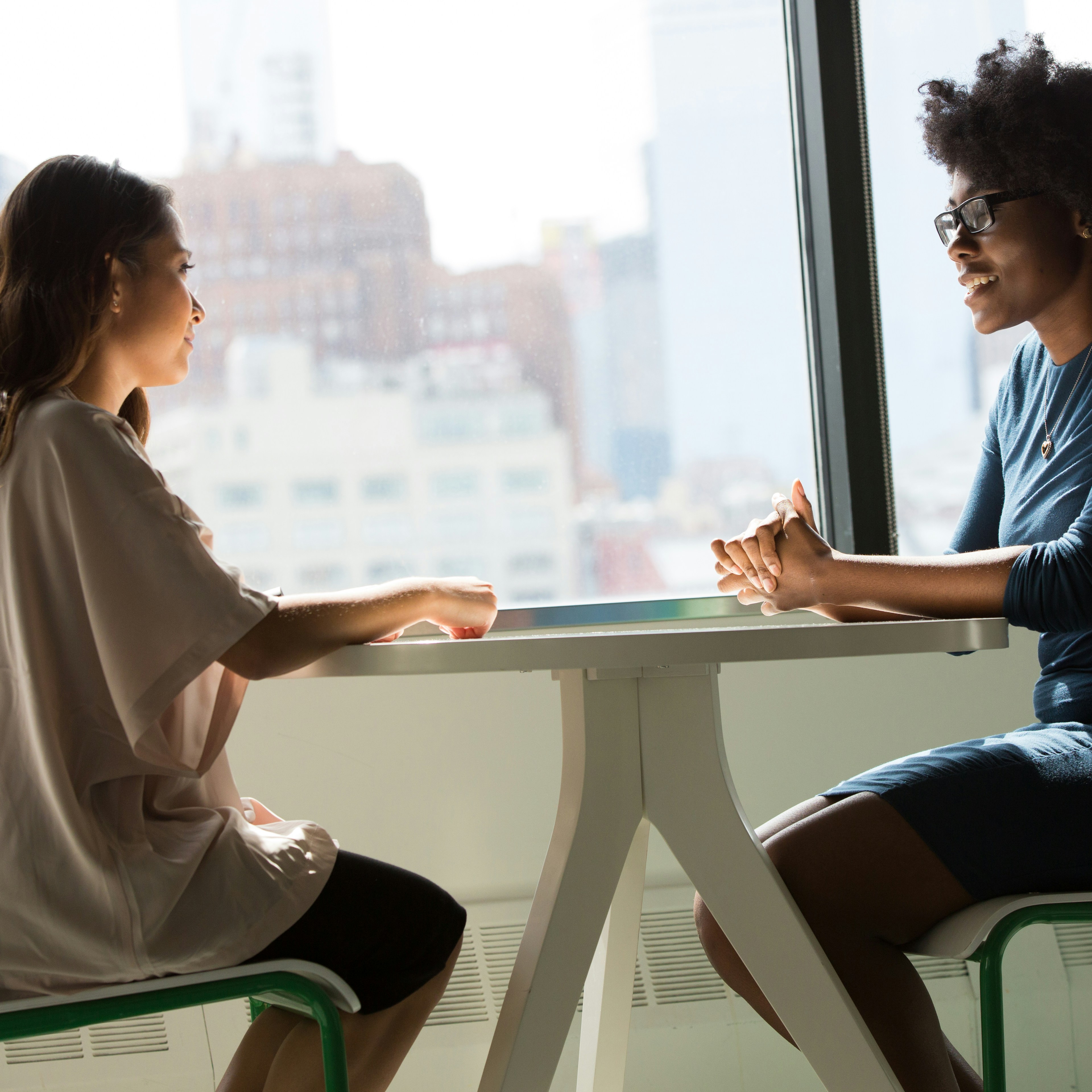 two women sitting beside table and talking