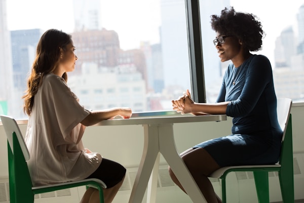 two women sitting beside table and talkingby Christina @ wocintechchat.com