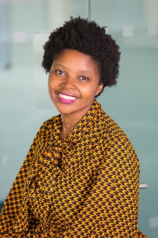Jodi smiling brightly in a colorful, patterned outfit that radiates joy and confidence.
