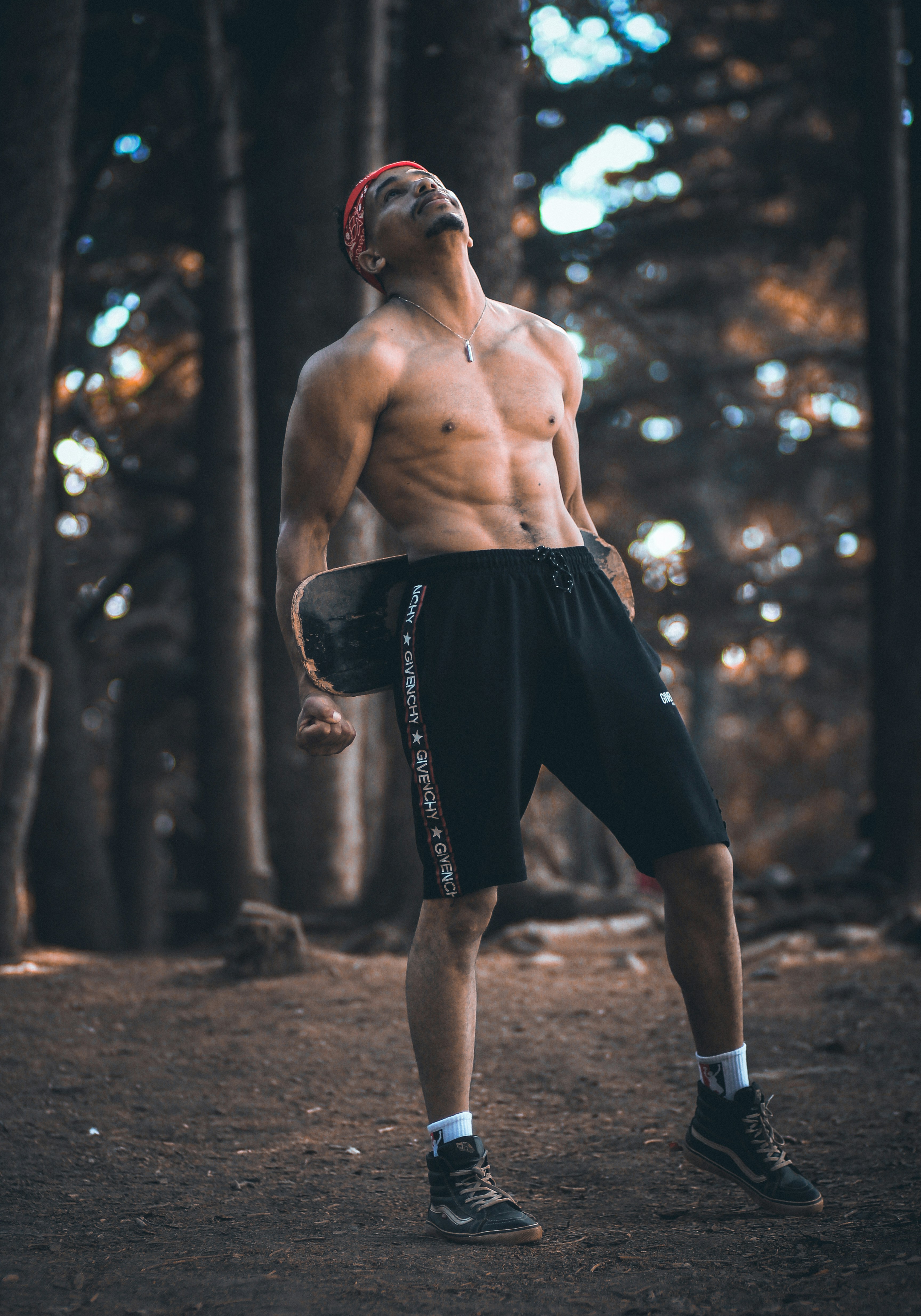 topless man wearing black shorts carrying skateboard