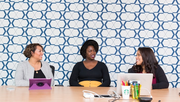 three women sitting on chairs front of table