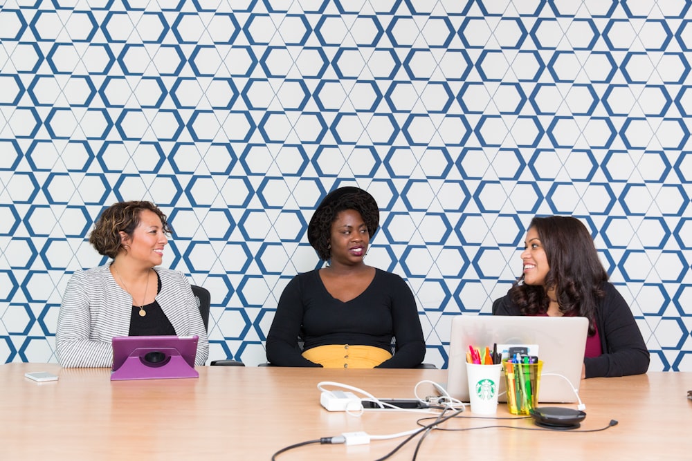 three women sitting on chairs front of table