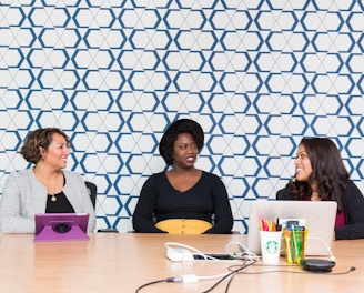 three women sitting on chairs front of table