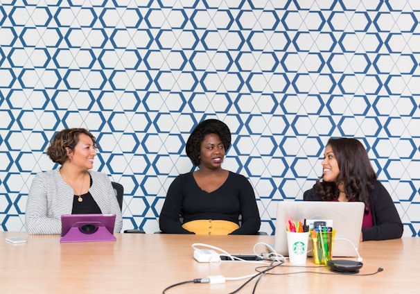 three women sitting on chairs front of table