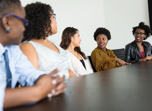 five people sitting at table and talking