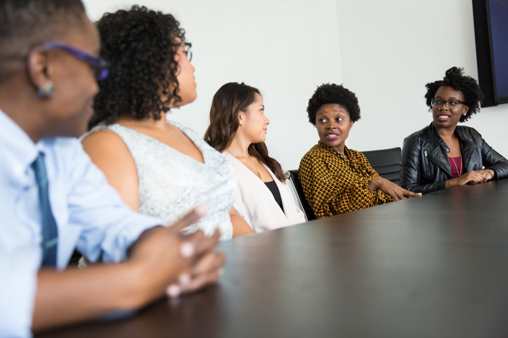 five people sitting at table and talking