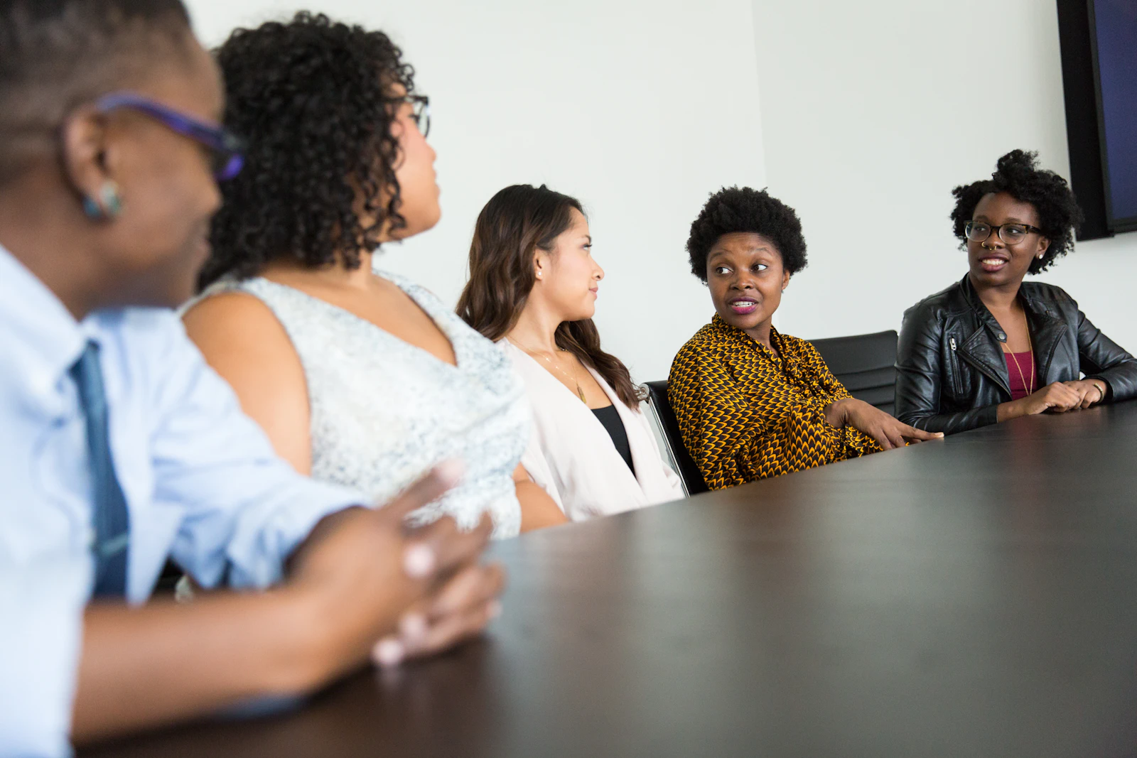 A diverse group of women collaborating around a table in a workspace.