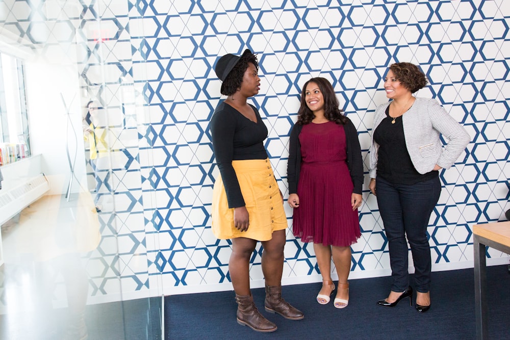 three standing women talking to each other