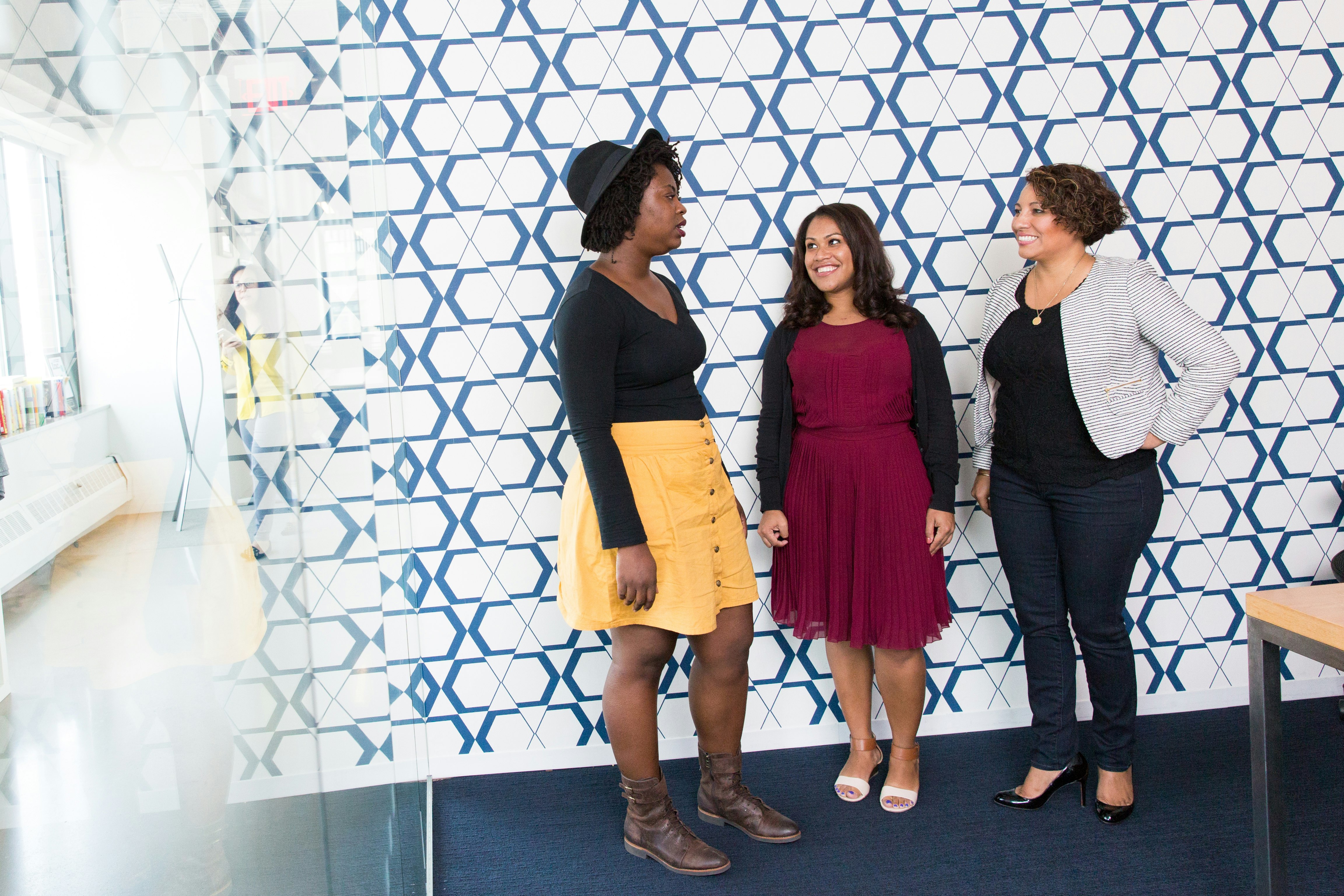 three standing women talking to each other