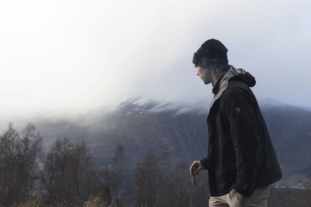 homme portant une veste noire regardant la montagne