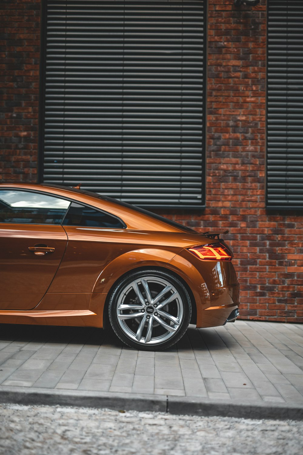 a brown sports car parked in front of a brick building