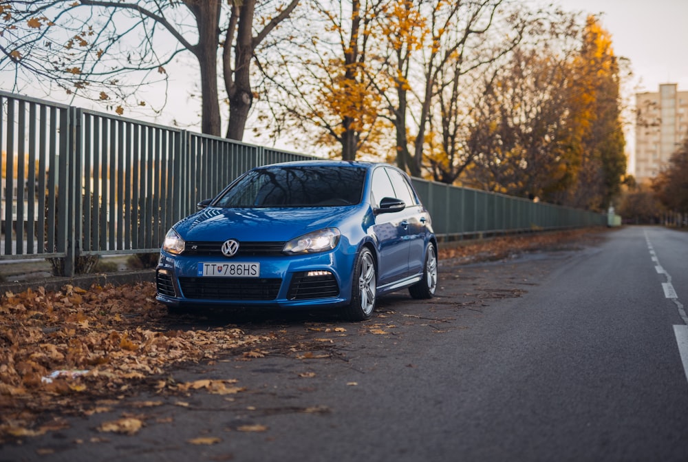 blue Volkswagen sedan beside road